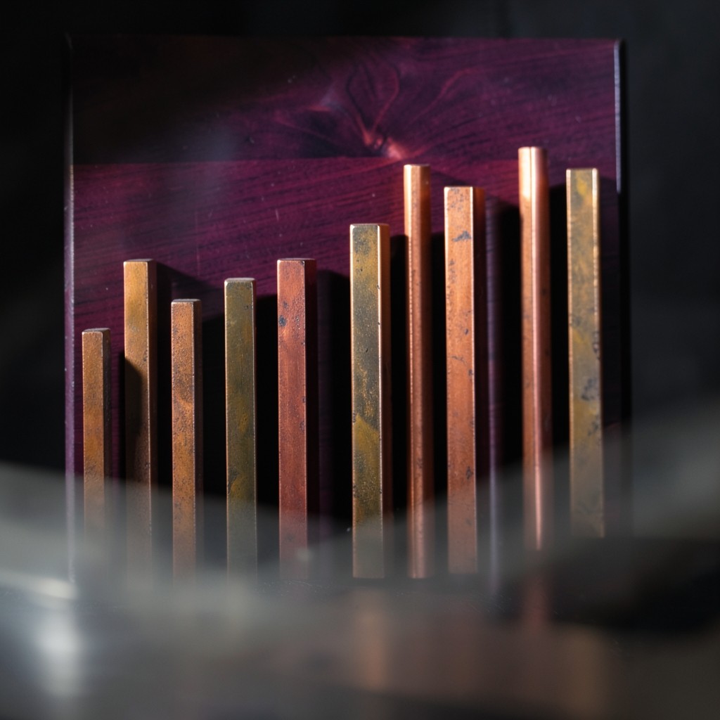A row of copper vertical bars of uneven height on a dark plum board